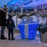 Blue and silver 3D gift box beside a winter ice-skating pavilion