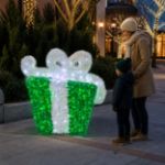 Green and white 3D gift box in an outdoor holiday plaza