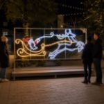 Santa and flying reindeer light sculpture in an outdoor holiday plaza