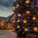 Closer view of lit Moravian stars on an evergreen tree