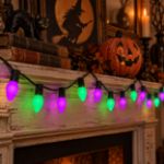 Purple and green RetroGlo C7 Halloween lights glowing in a decorated Halloween scene